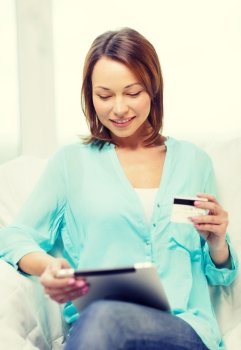 home, technology, online shopping and internet concept - smiling woman sitting on the couch with tablet pc at home