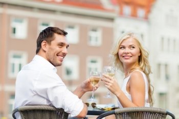 summer holidays and dating concept - smiling couple drinking wine in cafe in the city. smiling couple drinking wine in cafe