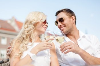 summer holidays and dating concept - smiling couple in sunglasses drinking wine in cafe. smiling couple in sunglasses drinking wine in cafe