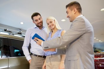 auto business, car sale, technology and people concept - happy couple with car dealer in auto show or salon