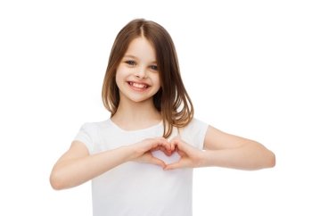 friendship, t-shirt design and happy people concept - smiling little girl in white blank t-shirts showing heart with hands