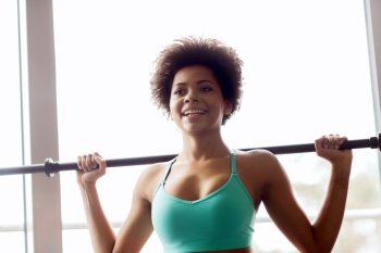 fitness, sport, training and people concept - happy smiling african american woman holding bar in gym
