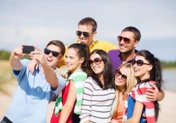summer holidays, vacation, happy people concept - group of friends taking selfie with cell phone on the beach