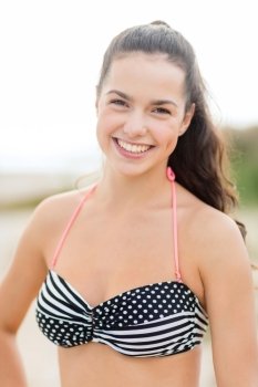 summer vacation, holidays and people concept - happy young woman in bikini swimsuit on beach