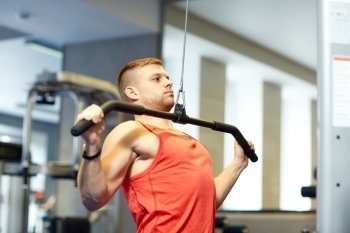 sport, fitness, bodybuilding, lifestyle and people concept - man exercising and flexing muscles on cable machine in gym