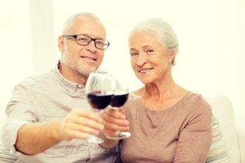 family, holidays, drinks, age and people concept - happy senior couple with glasses of red wine at home