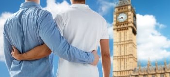 people, homosexuality, same-sex marriage, travel and love concept - close up of happy male gay couple hugging from back over big ben tower in london background