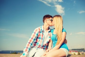 holidays, vacation, love and friendship concept - smiling couple kissing outdoors