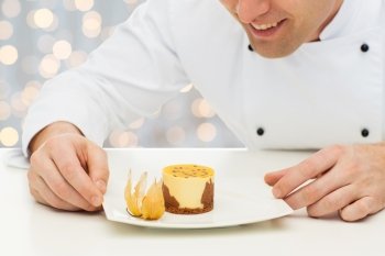 cooking, profession, haute cuisine, food and people concept - close up of happy male chef cook decorating dessert over holidays lights background