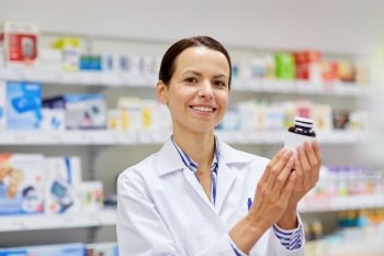 medicine, pharmaceutics, health care and people concept - happy female pharmacist with drug jar at pharmacy