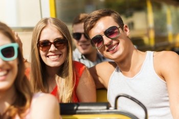 friendship, travel, vacation, summer and people concept - group of smiling teenage friends and couple in sunglasses traveling by tour bus
