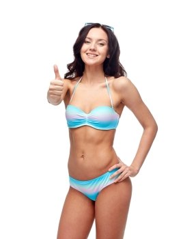 people, fashion, swimwear, summer and beach concept - happy young woman in bikini swimsuit showing thumbs up gesture