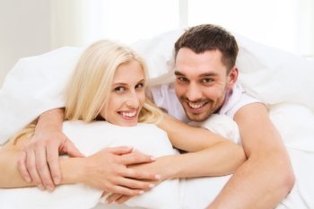 people, rest, relationships and happiness concept - happy couple in bed at home
