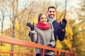 love, gesture, family, season and people concept - smiling couple hugging on bridge in autumn park
