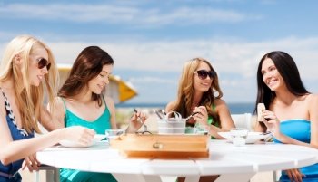 summer holidays and vacation - girls eating and drinking in cafe on the beach. girls in cafe on the beach