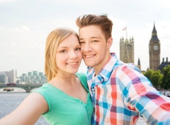 travel, vacation, technology and friendship concept - happy couple taking selfie over big ben and thames river in london background