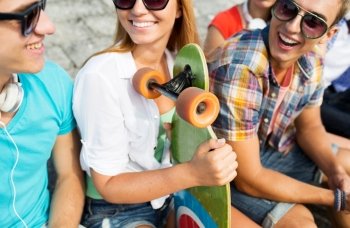 people, leisure, communication and sport concept - close up of happy teenage friends with longboard talking on city street
