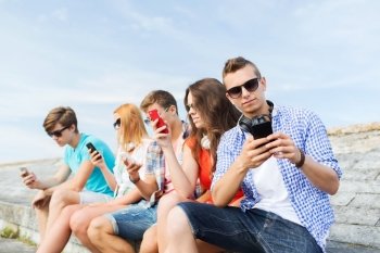 friendship, leisure, summer, technology and people concept - group of friends with smartphone outdoors