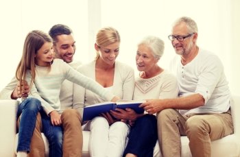 family, happiness, generation and people concept - happy family with book or photo album sitting on couch at home