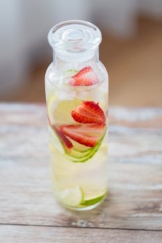 healthy eating, drinks, diet and detox concept - close up of fruit water with lime, lemon and cucumber in glass bottle