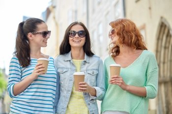 vacation, weekend, takeaway drinks, leisure and friendship concept - smiling happy young women or teenage girls drinking coffee from disposable paper cups on city street