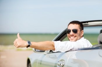 auto business, transport, leisure and people concept - happy man driving cabriolet car and showing thumbs up