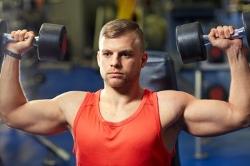 sport, fitness, bodybuilding, lifestyle and people concept - young man with dumbbells flexing muscles in gym