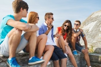 people, leisure and communication concept - group of happy teenage friends talking outdoors