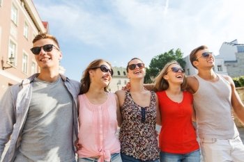friendship, travel, tourism, summer vacation and people concept - group of smiling teenagers walking in city