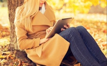 season, technology and people concept - young woman with tablet pc computer in autumn park