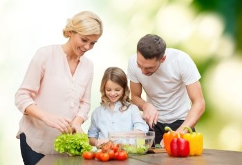 vegetarian food, culinary, happiness and people concept - happy family cooking vegetable salad for dinner over green natural background