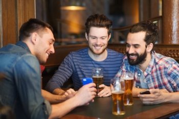 people, men, leisure, friendship and technology concept - happy male friends with smartphones drinking beer at bar or pub