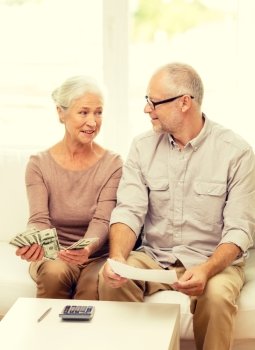 family, business, savings, age and people concept - smiling senior couple with papers, money and calculator at home