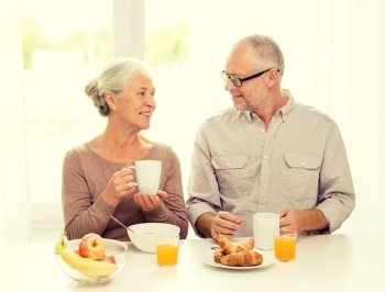 family, technology, food, drinks and people concept - happy senior couple having breakfast at home