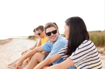 summer holidays, vacation, tourism, travel and people concept - group of happy friends sitting on beach