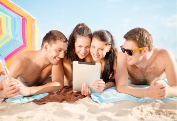 summer holidays, vacation, technology and people concept - group of happy friends with tablet pc computer sunbathing on beach