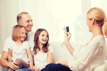 family, children, photography and home concept - smiling happy mother taking picture of father and two daughter at home