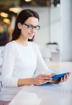 leisure, business, people, technology and lifestyle concept - smiling young woman in eyeglasses with tablet pc computer at cafe