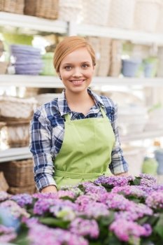 people, gardening and profession concept - happy woman with flowers in greenhouse