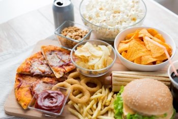 fast food and unhealthy eating concept - close up of fast food snacks and coca cola drink on wooden table. close up of fast food snacks and drink on table