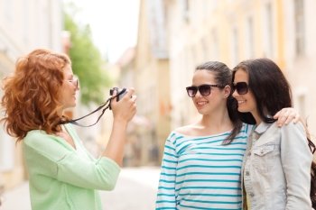 tourism, travel, leisure, holidays and friendship concept - smiling teenage girls with camera outdoors