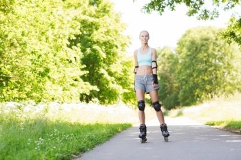 fitness, sport, summer, rollerblading and healthy lifestyle concept - happy young woman in rollerblades and protective gear riding outdoors