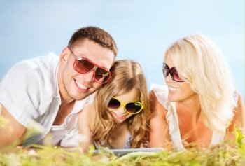 summer holidays, children and people concept - happy family with tablet pc, blue sky and green grass