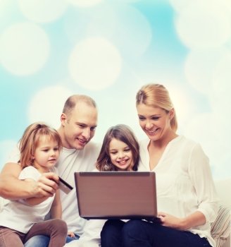 family, holidays, shopping, technology and people - happy family with laptop computer and credit card over blue lights background