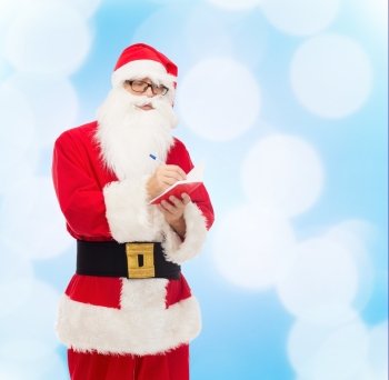 christmas, holidays and people concept - man in costume of santa claus with notepad and pen over blue lights background