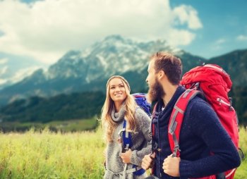 adventure, travel, tourism, hike and people concept - smiling couple walking with backpacks over alpine mountains background