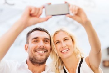 love, date, technology, people and relations concept - smiling happy couple taking selfie with smartphone outdoors