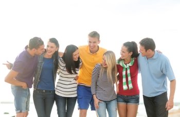 summer holidays, vacation, tourism, travel and people concept - group of happy friends talking on beach