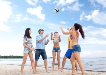 summer holidays, sport, leisure and people concept - group of happy friends playing beach ball