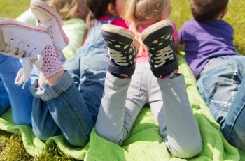 summer, childhood, leisure and people concept - close up of happy kids lying on picnic blanket outdoors